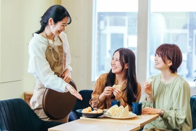レストランで食事する女性とホールスタッフ
